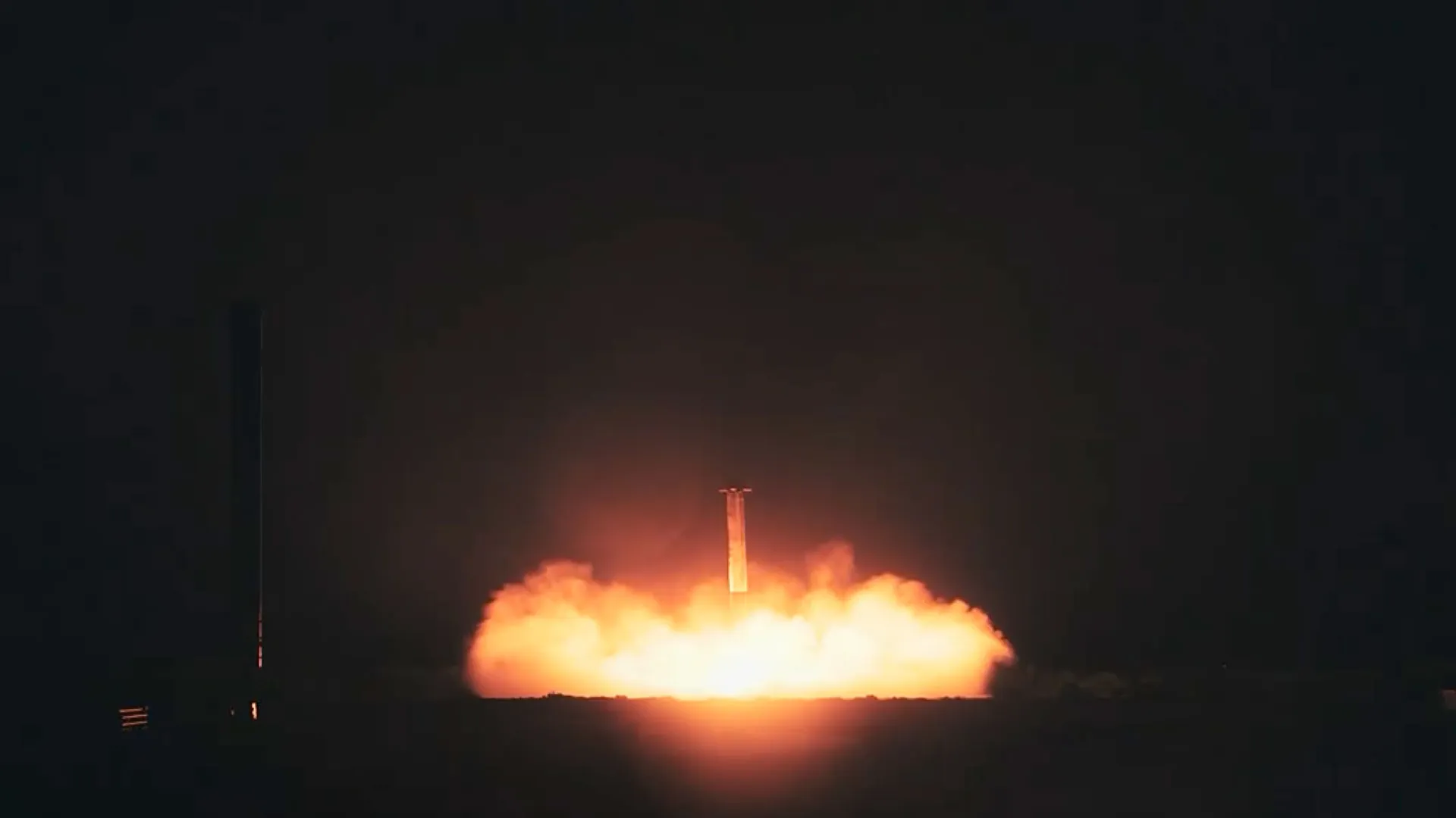 eine Raketenstufe gibt eine orangefarbene Rauchfahne ab, als sie ihr Triebwerk zündet, um in der Dunkelheit der Nacht zu landen.