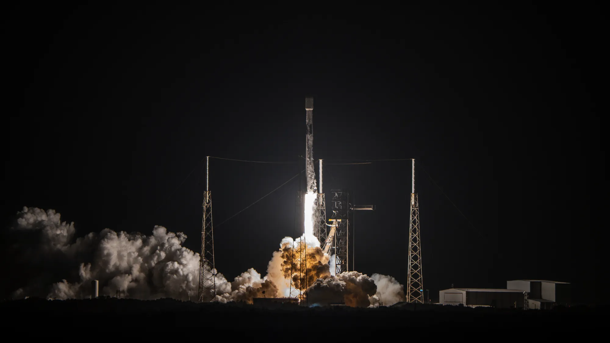 eine schwarz-weiße Rakete startet in einen dunklen Nachthimmel